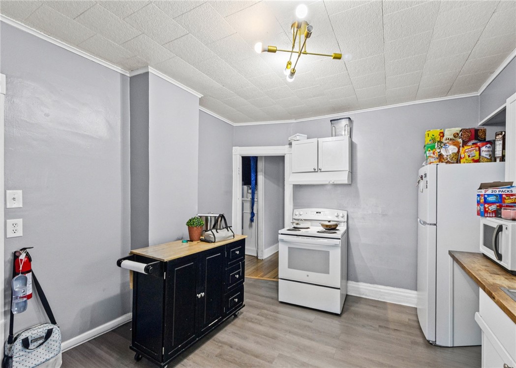 Kitchen with a black rolling island and white stove and refrigerator.