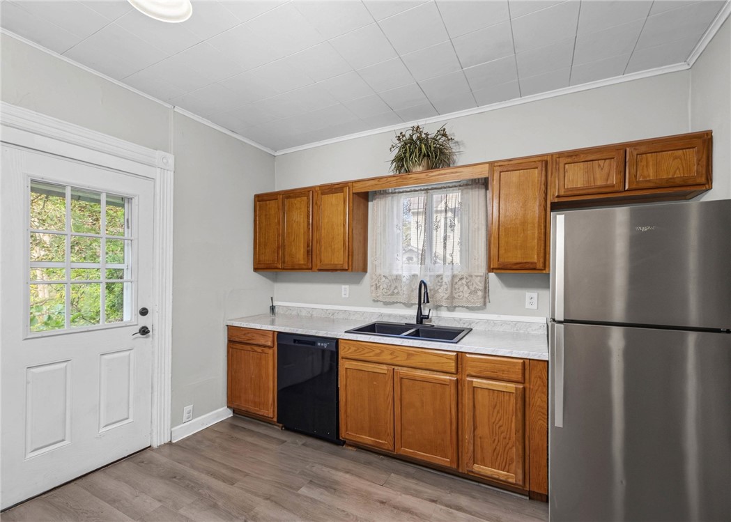 Kitchen with warm wood cabinets, marble-look counters, and a stainless steel refrigerator.
