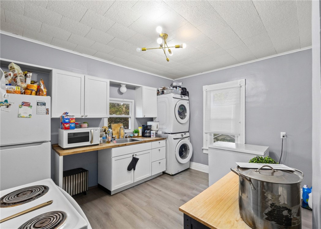 Kitchen with white cabinetry, wood counters, and a stacked washer and dryer.