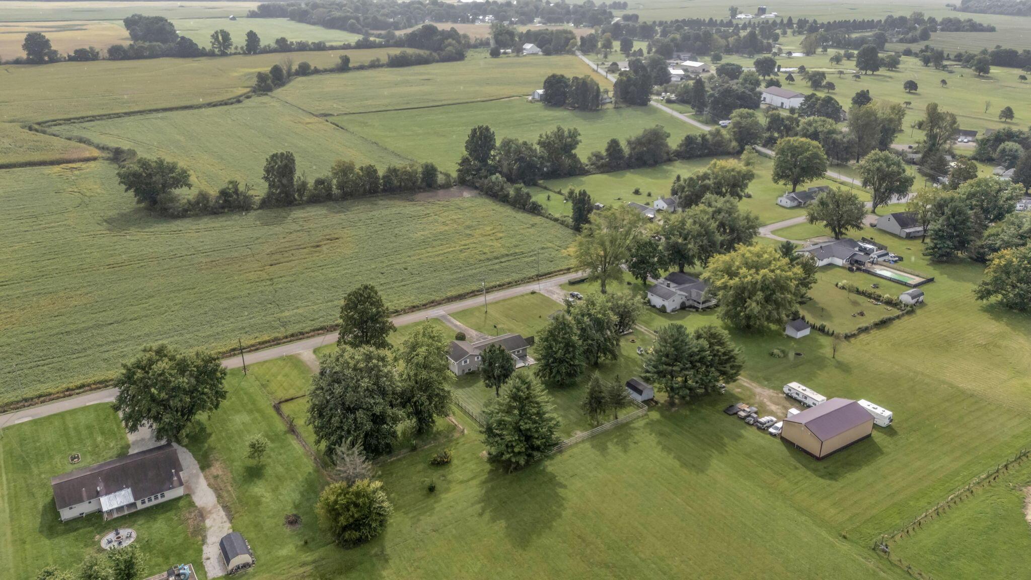 Aerial view of green fields beside a country road, with scattered homes and outbuildings.