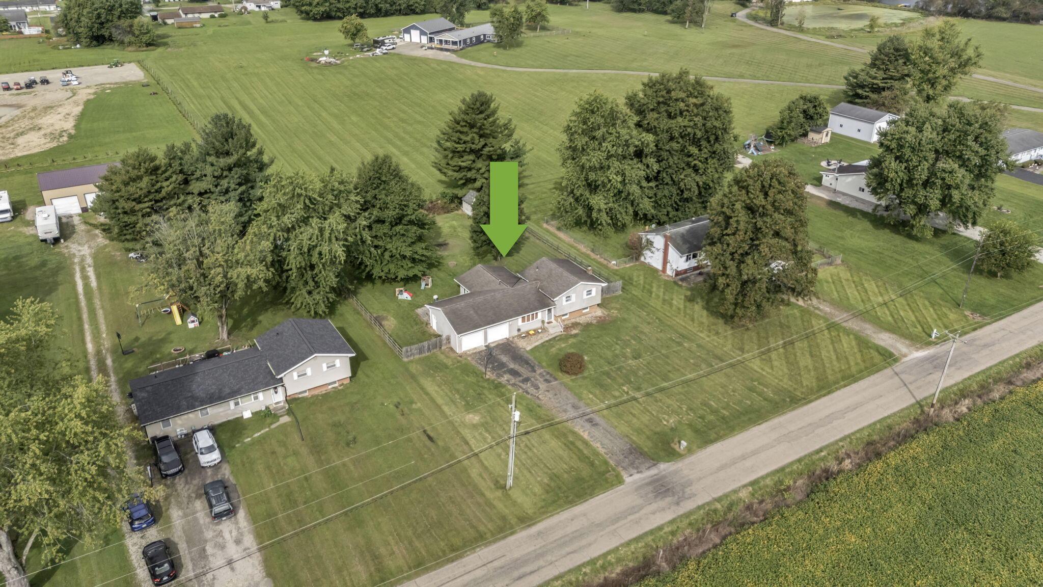Aerial view of a gray home and its lawn, marked by a green arrow.