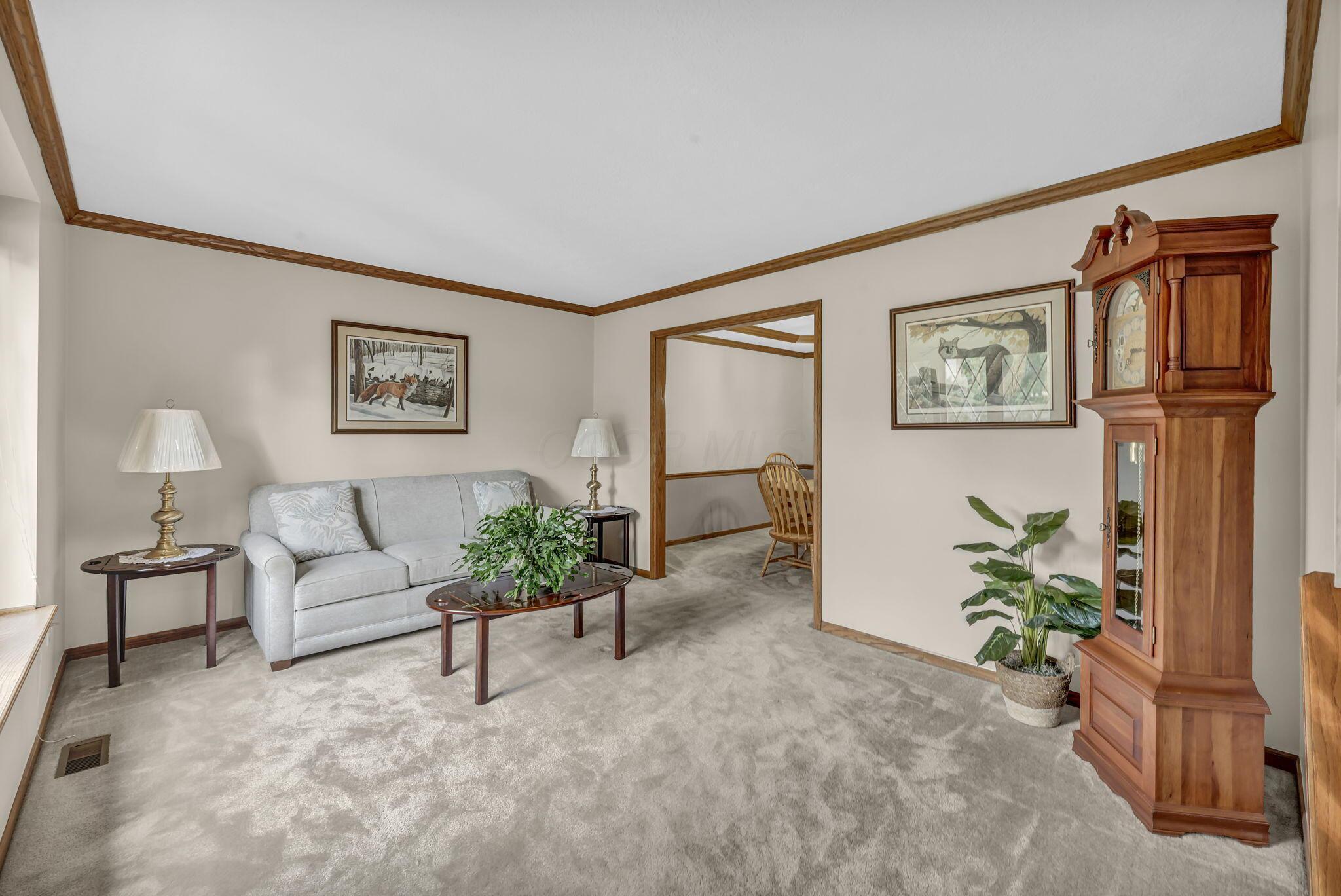 Living room with a gray sofa, vaulted wood-trimmed ceiling, and a tall wooden grandfather clock.