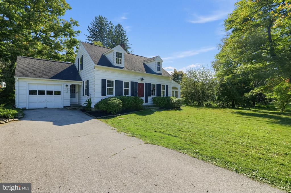 White clapboard house with two dormers, an attached garage, and a red front door.