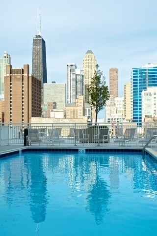 Rooftop pool with lounge chairs and the Chicago skyline, including the Willis Tower.