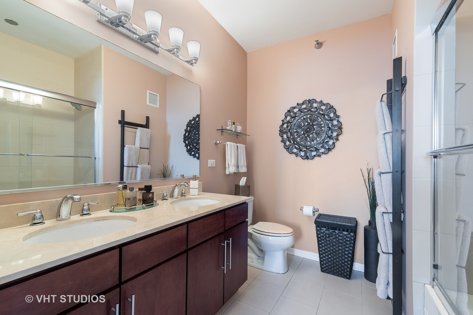 Bathroom with a dark double vanity, large mirror, and glass-enclosed shower.