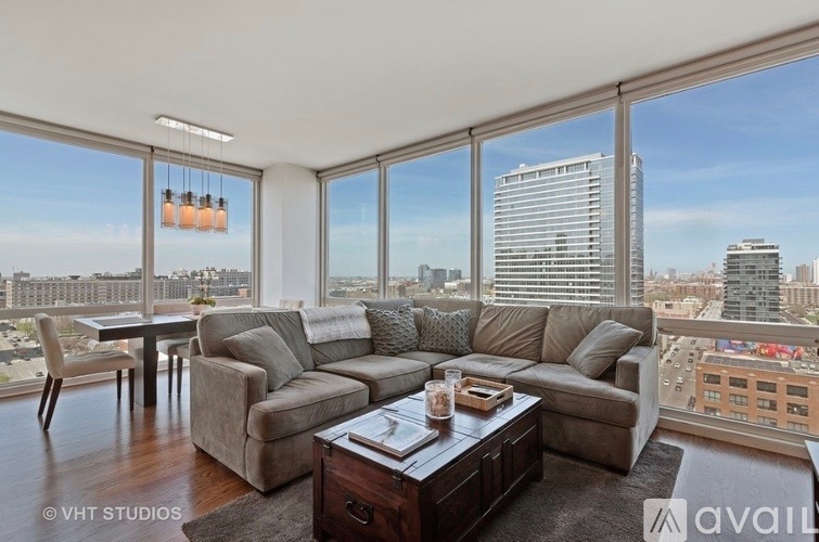 Living room with a gray sectional and floor-to-ceiling windows overlooking the city.