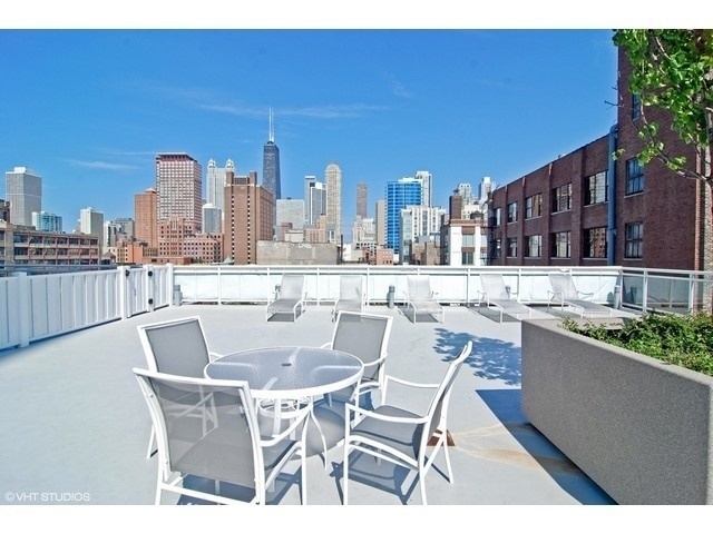 Rooftop terrace with white patio furniture and a view of the Chicago skyline.