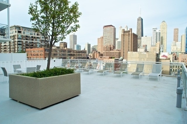 Rooftop terrace with white lounge chairs and a leafy planter overlooking the Chicago skyline.
