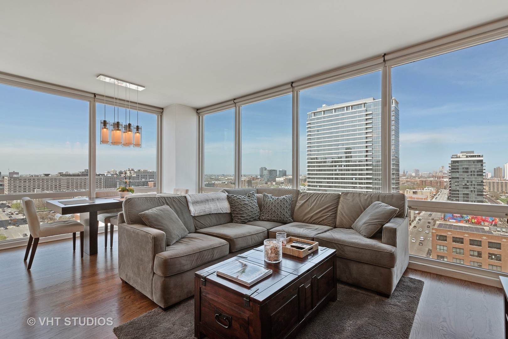 High-rise condo living room with a sectional sofa and floor-to-ceiling windows overlooking the city.