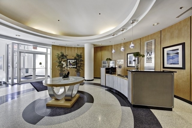 Condominium lobby with a curved reception desk and a circular-patterned terrazzo floor.