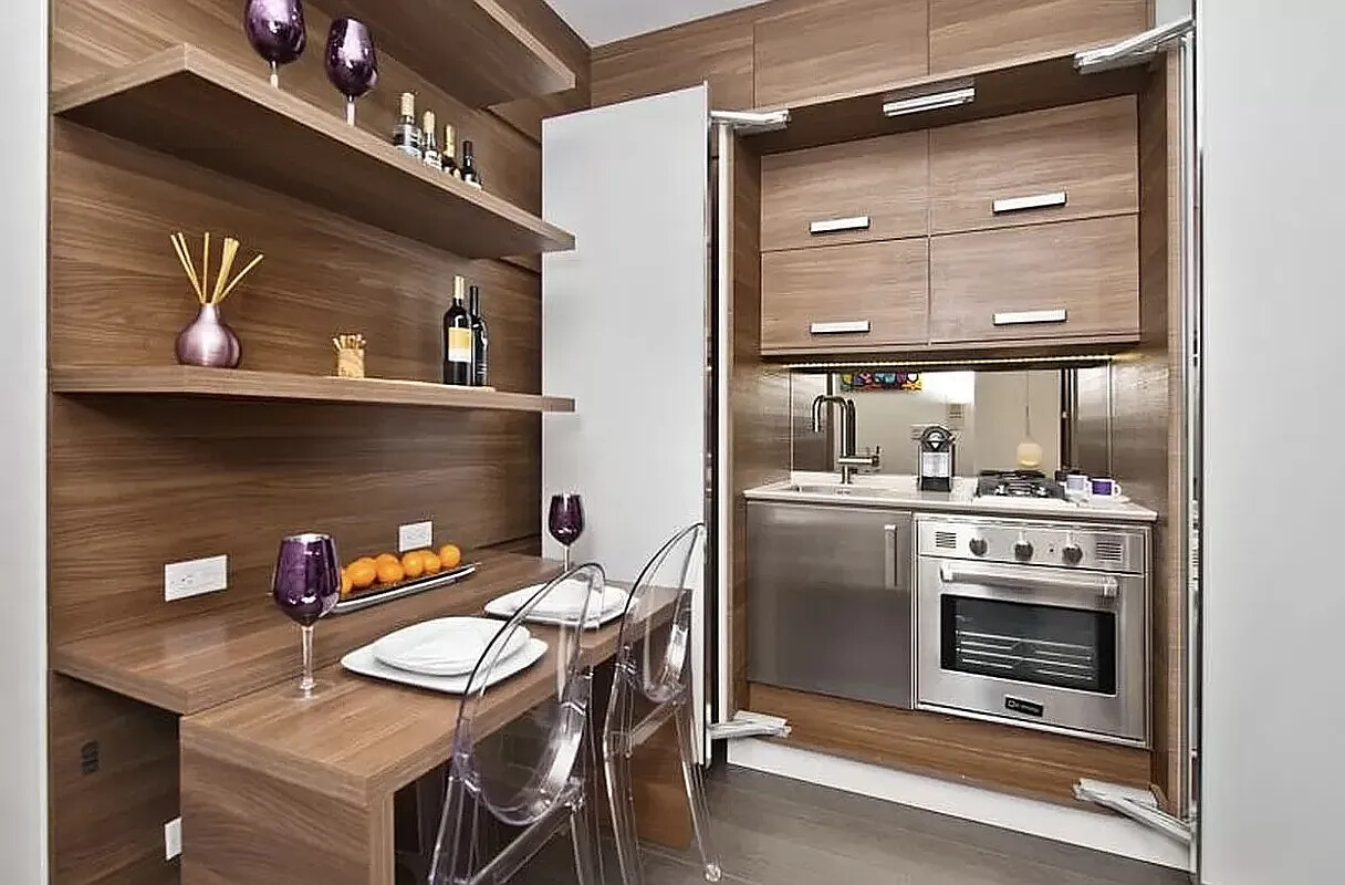 Wood-paneled kitchen with concealed appliances and a dining ledge set with plates and wine glasses.