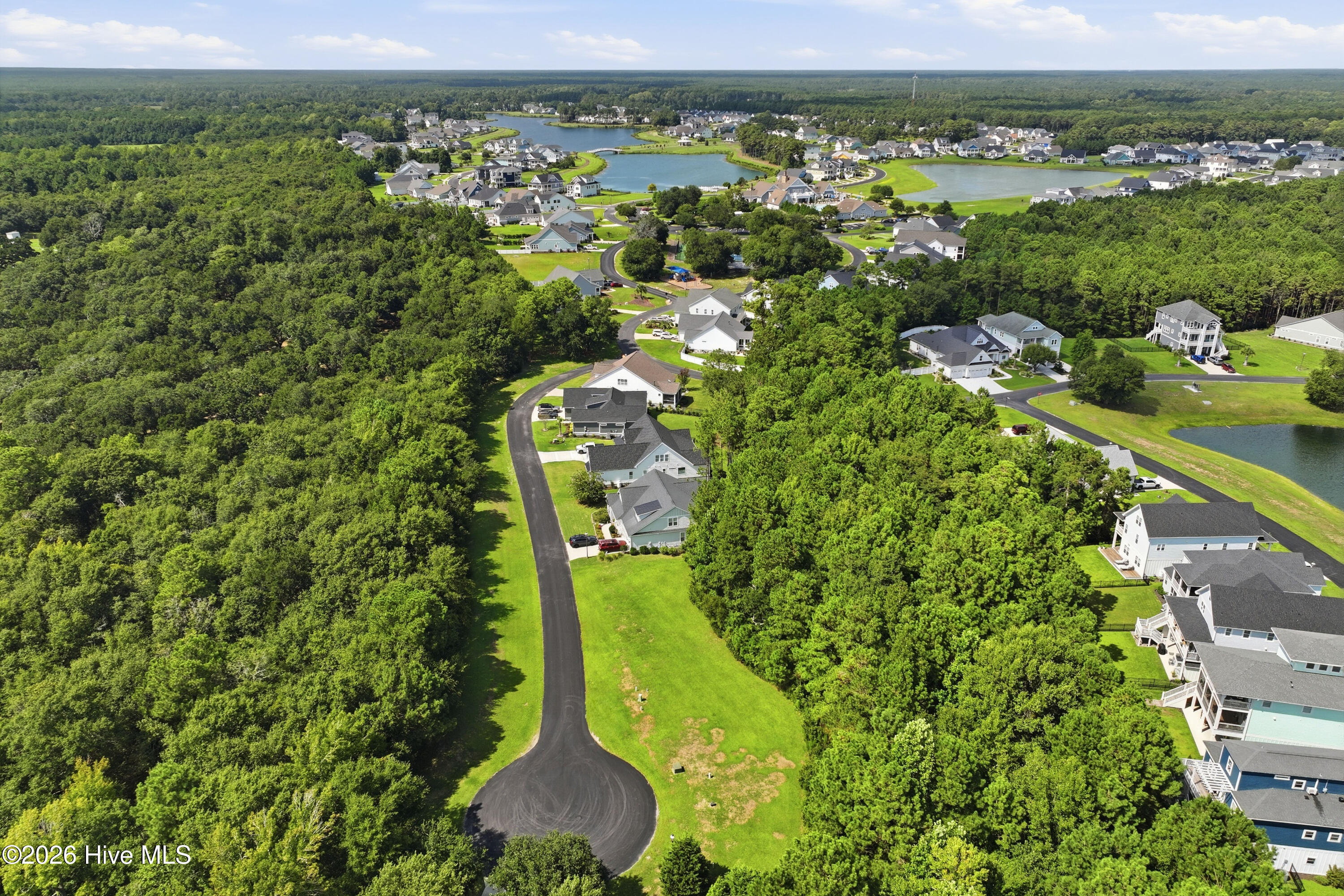 Aerial view of a neighborhood with winding roads, wooded areas, and ponds.