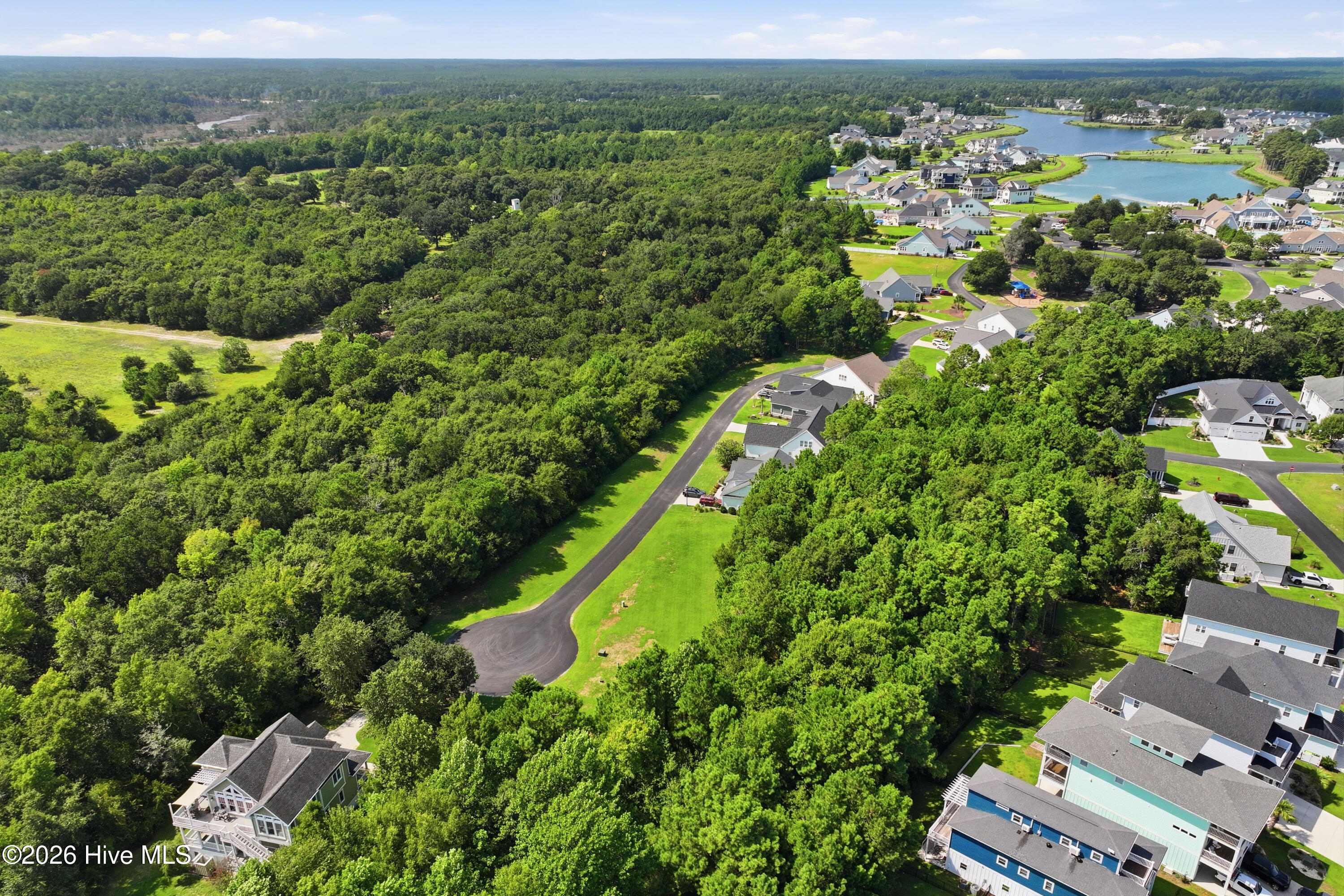 Aerial view of a wooded area beside homes, winding roads, and neighborhood ponds.