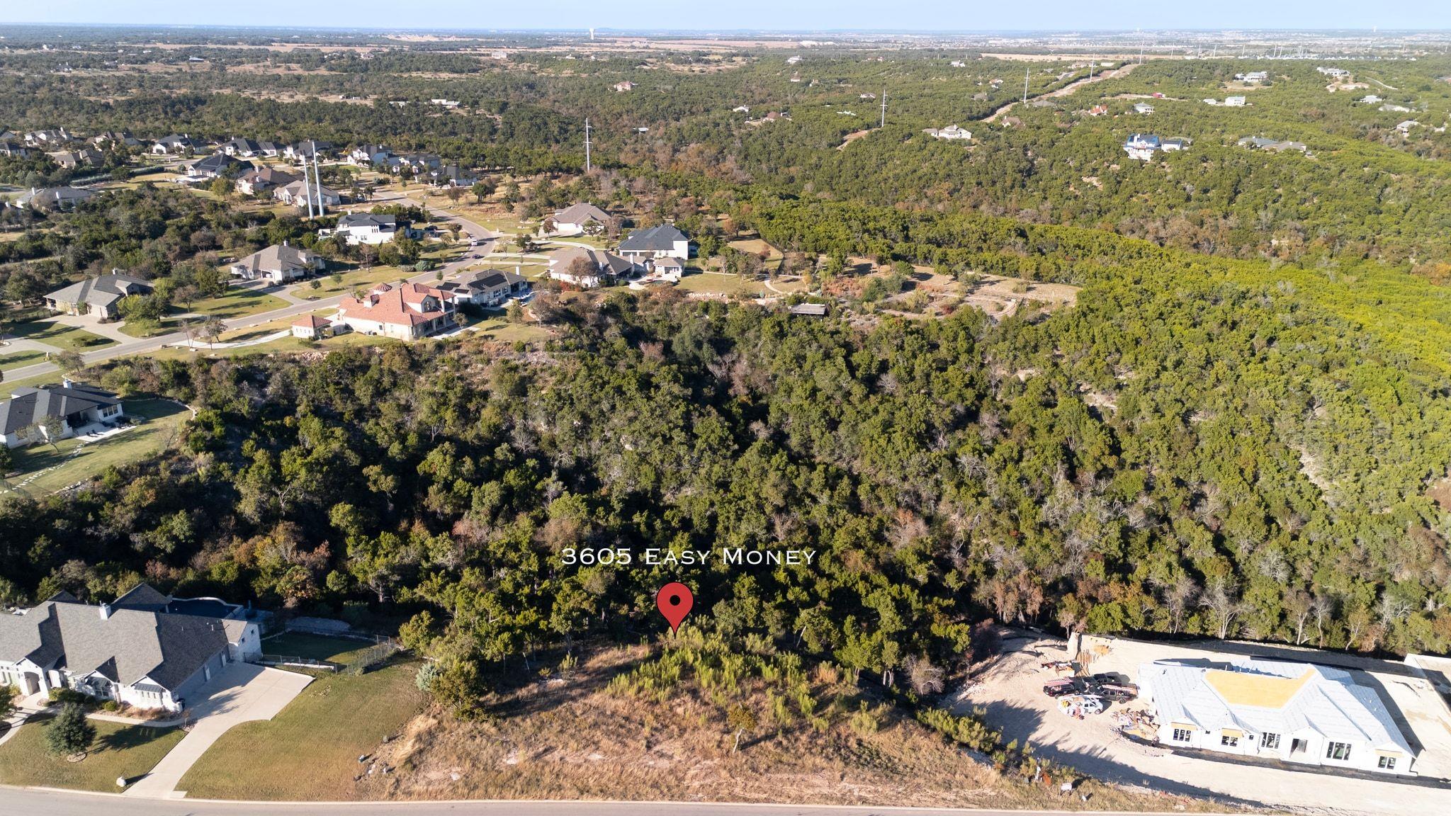 Aerial view of wooded residential lots, nearby homes, and a house under construction, marked “3605 EASY MONEY.”