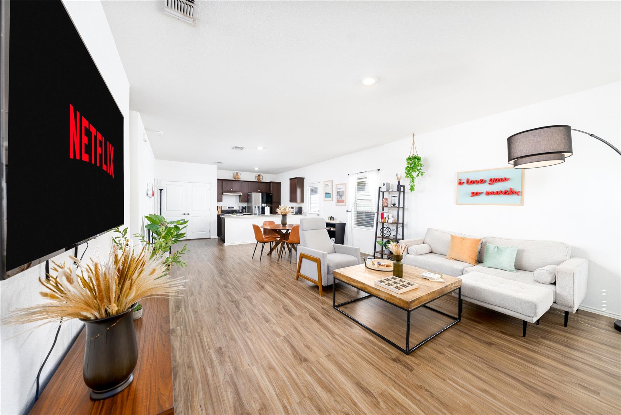 Open-plan living room with a light sectional, wood coffee table, and television displaying Netflix.