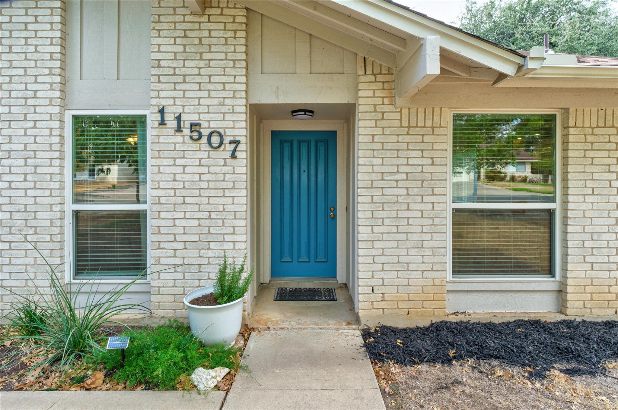 Brick home entrance with a recessed blue front door and address number 11507.