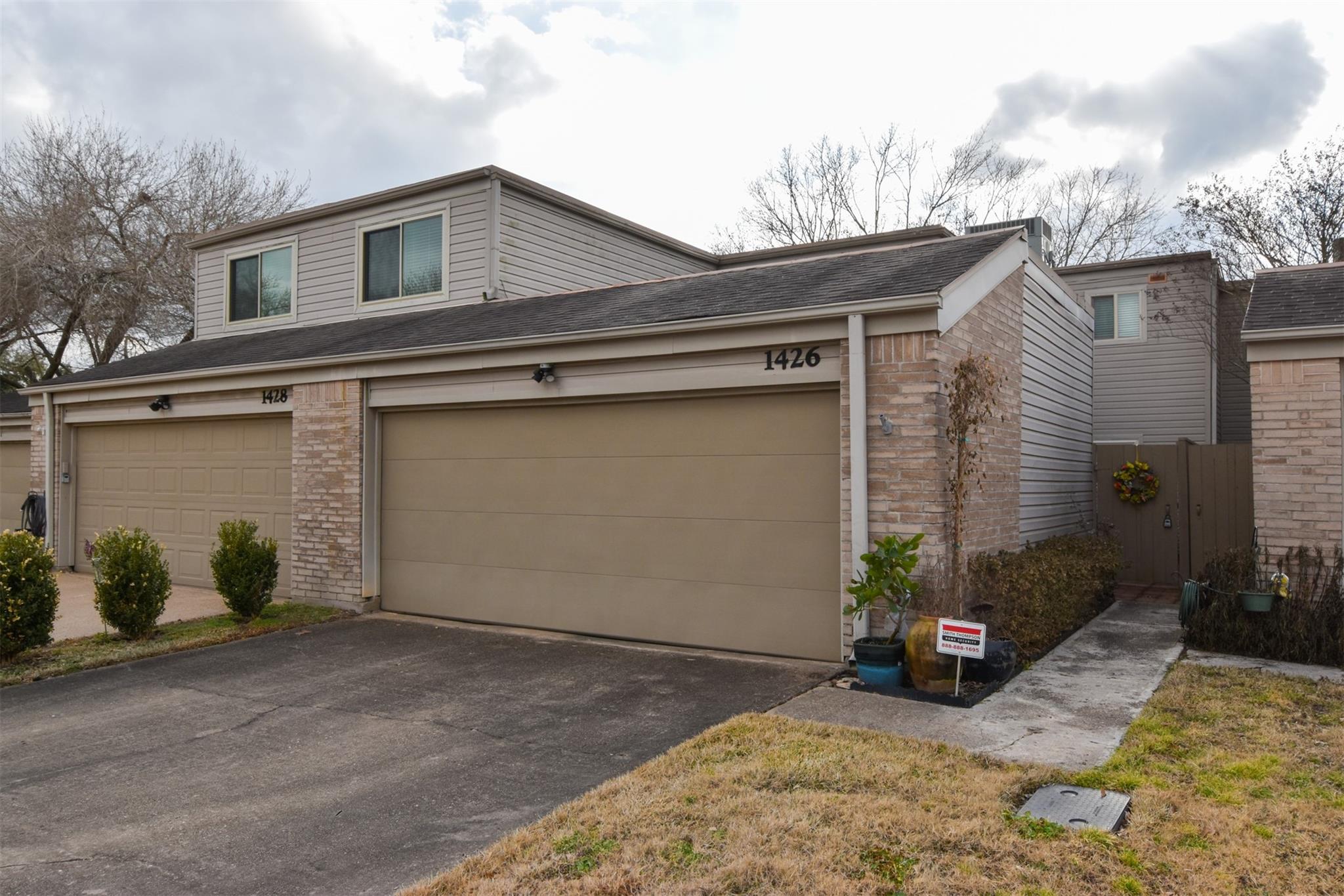 Two-story townhouse exterior with beige siding, brick accents, and a large garage marked 1426.