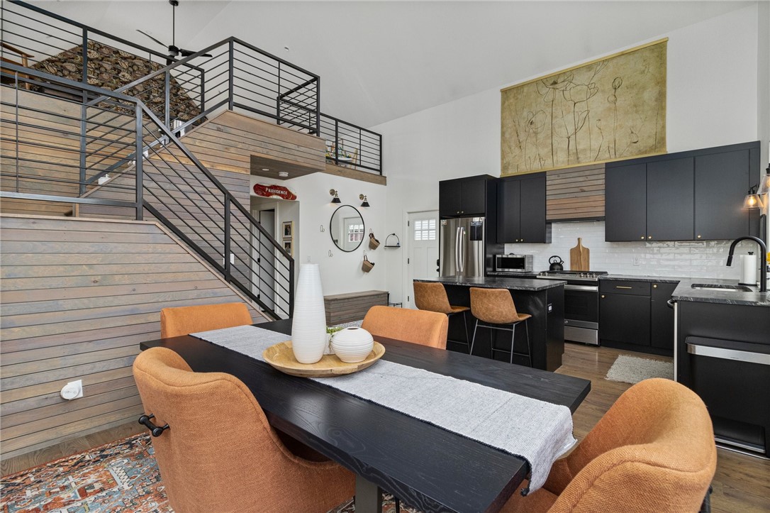 Open dining area and kitchen with a wooden loft staircase and dark cabinetry.