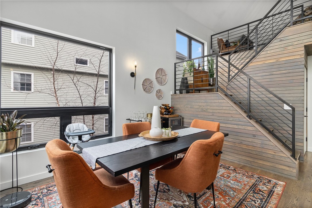 Dining area with orange chairs, a patterned rug, and a staircase leading to an upper level.