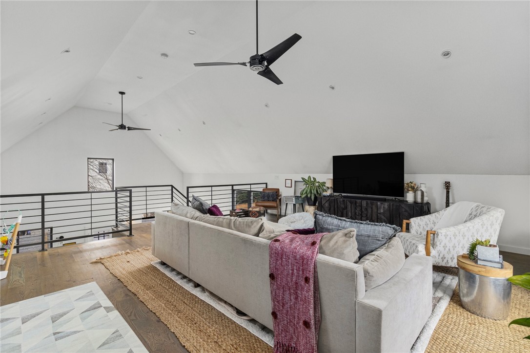 Loft living room with a vaulted ceiling, black mezzanine railing, and large sectional sofa.