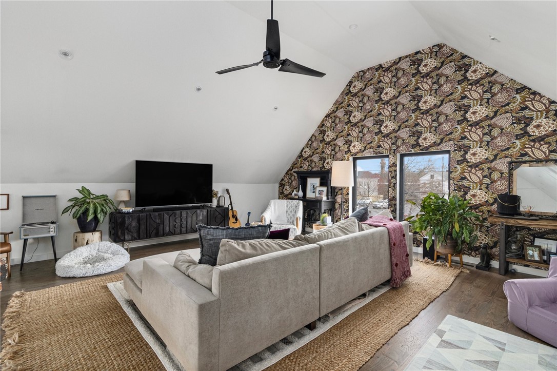 Living room with a beige sectional, bold patterned accent wall, and sloped ceiling.