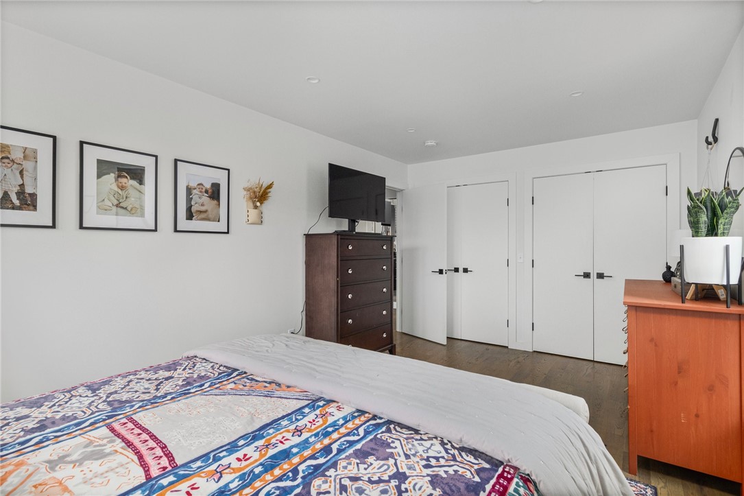 Bedroom with a colorful patterned quilt, framed photos, and dark wood furniture.