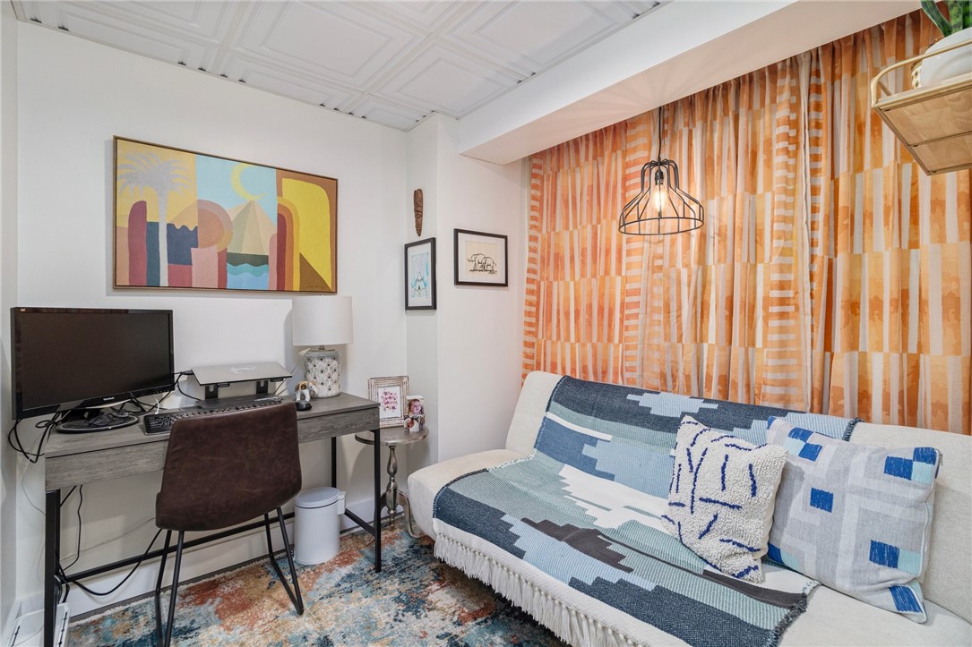 Living room with a white sofa, blue patterned textiles, orange curtains, and a compact desk area.