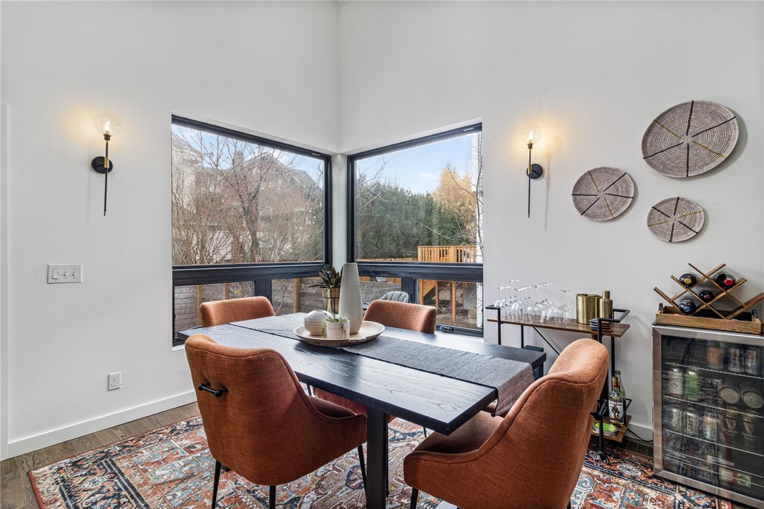 Dining room with corner windows, a dark table, rust-colored chairs, and a patterned rug.