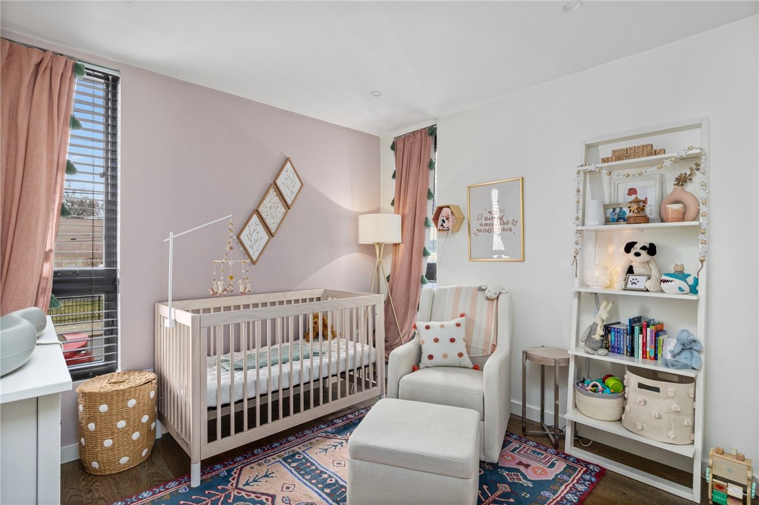 Nursery with a light wood crib, rocking chair, and colorful patterned rug.