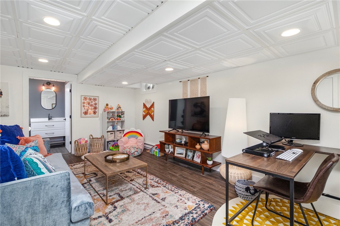 Furnished living room with a blue sofa, patterned rug, television, desk, and children’s play area.