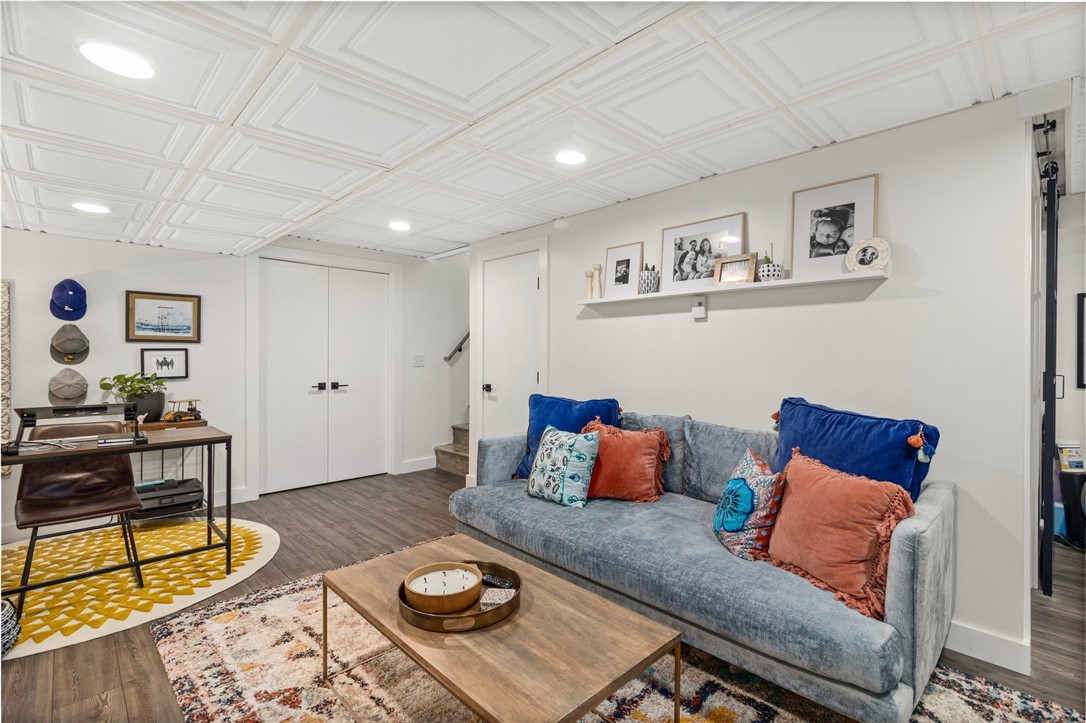 Living room with a gray sofa, colorful cushions, patterned rugs, and a decorative coffered ceiling.