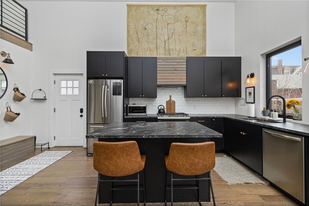 Kitchen with black cabinets, a large stone island, and brown leather bar stools.