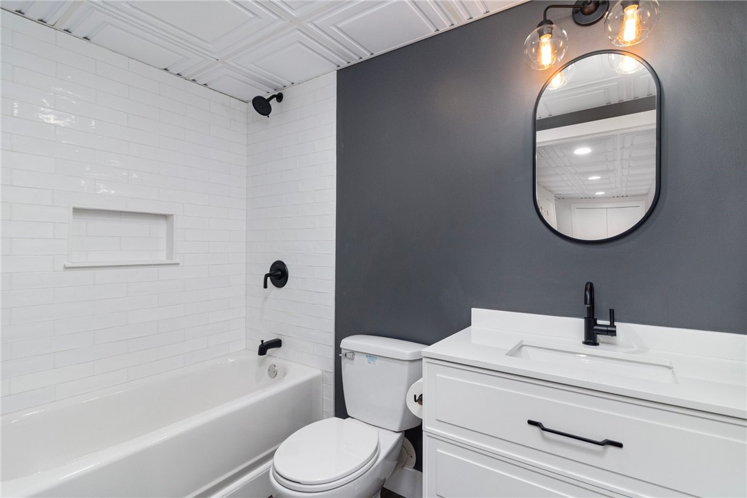 Bathroom with white subway tile, black fixtures, and a white vanity against a charcoal wall.
