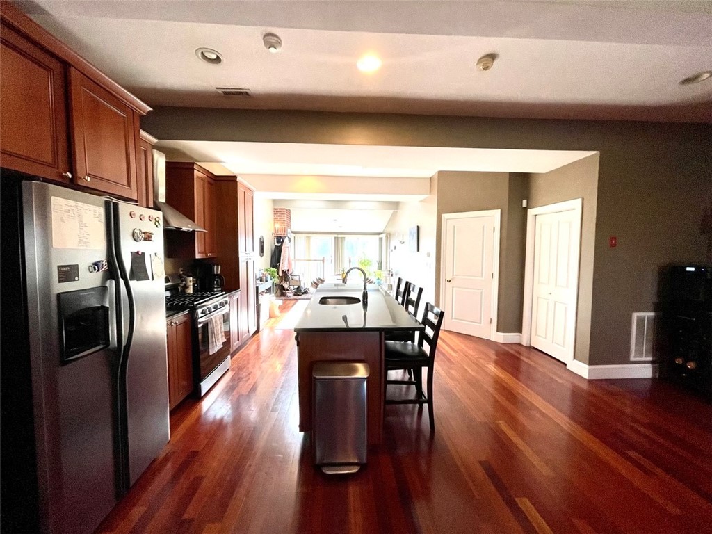 Kitchen with dark wood cabinetry, stainless steel appliances, and a central island with a sink.
