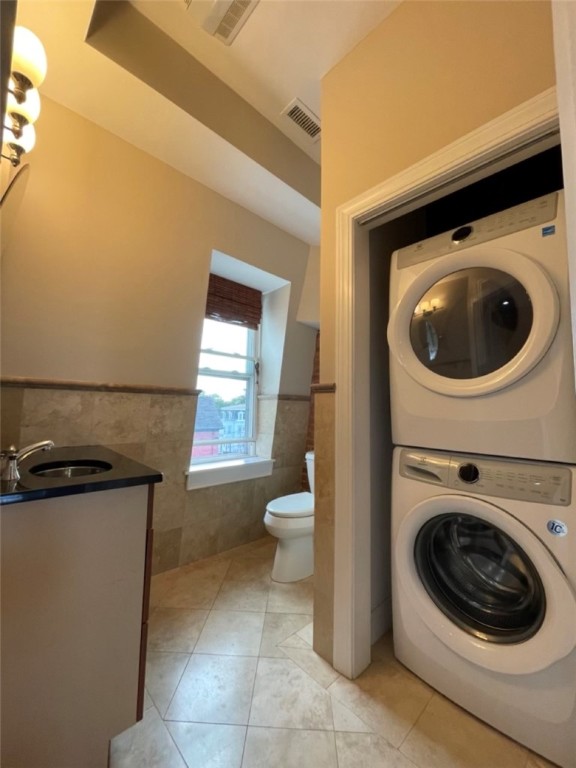 Bathroom with stacked washer and dryer, vanity sink, toilet, and window.
