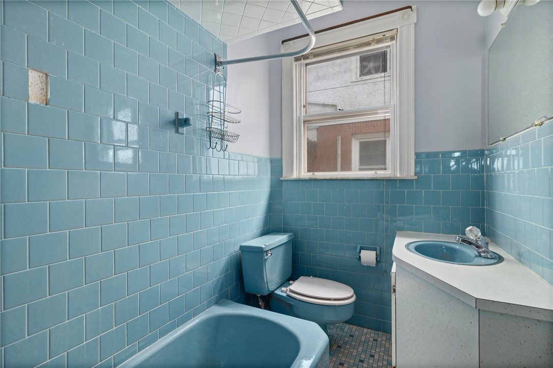 Bathroom with blue tile, a matching bathtub and toilet, and a white vanity with a blue sink.