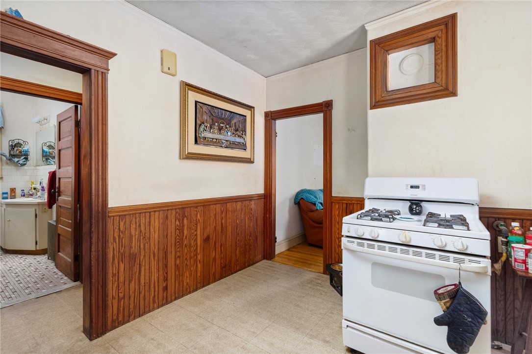 Kitchen with a white gas stove, wood-paneled walls, and an open doorway to a bathroom.