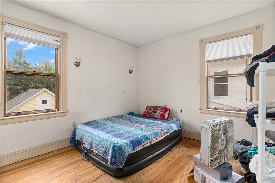 Bedroom with an air mattress, blue patterned blanket, two windows, and hardwood floors.