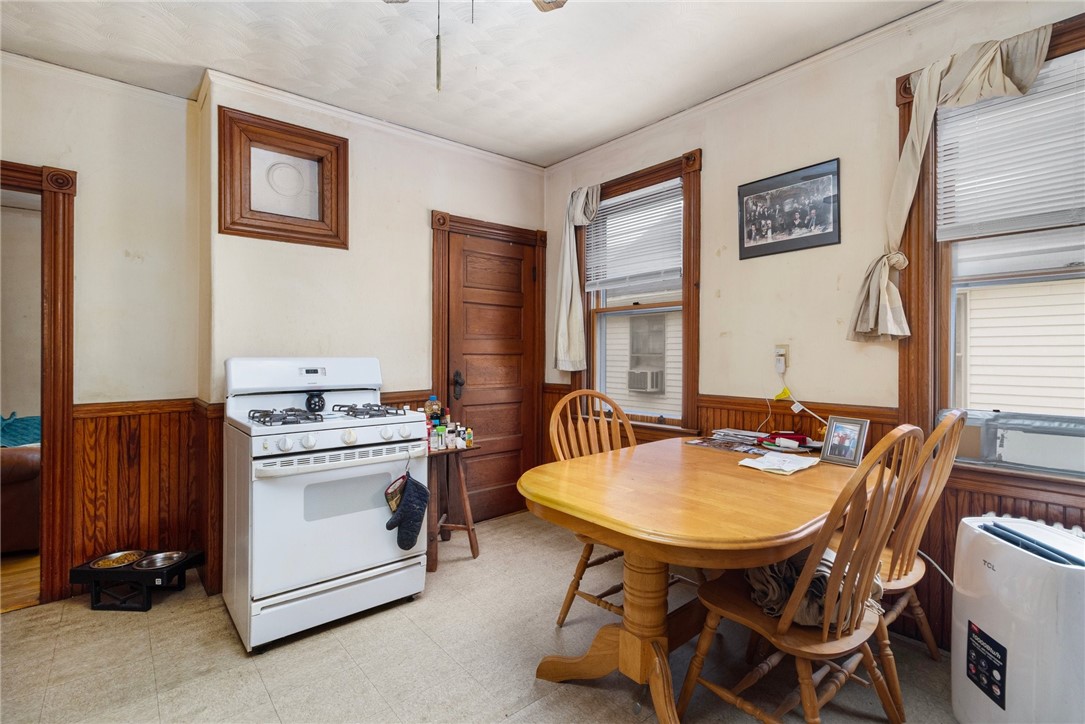 Kitchen dining area with a wooden table, gas range, and dark wood wainscoting.