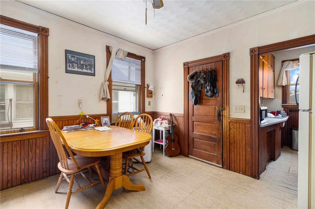 Dining room with a wooden table, paneled walls, and an adjoining kitchen.