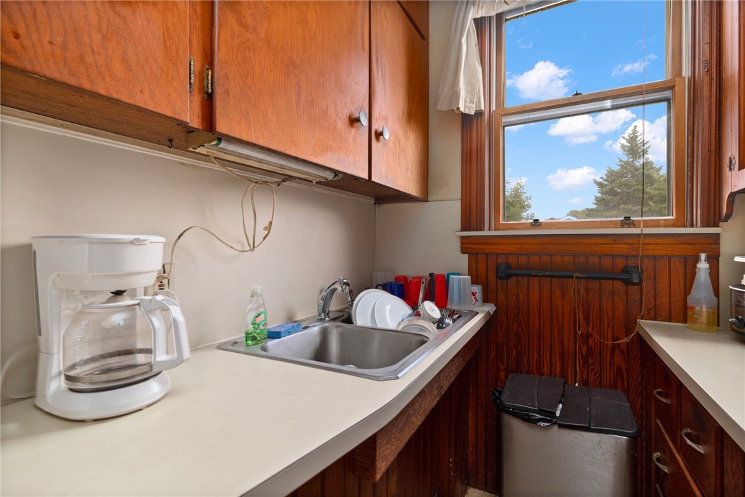 Kitchen with a stainless-steel sink, dark wood cabinets, and a large window.