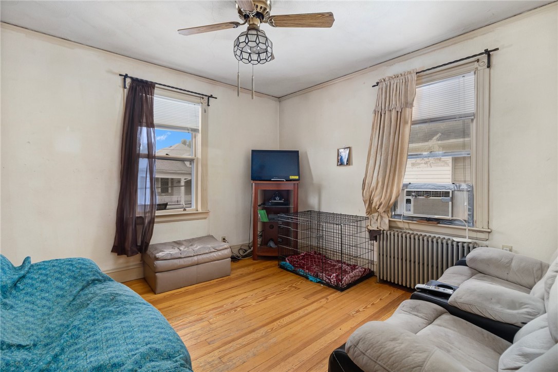 Living room with hardwood floors, two curtained windows, sofas, and a dog crate.