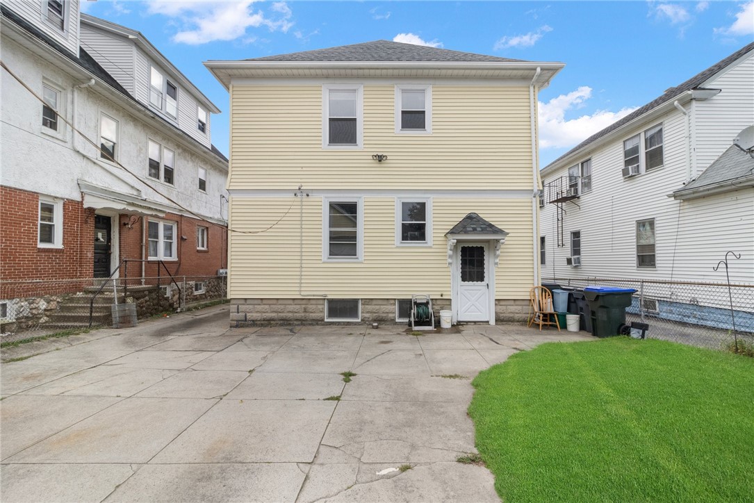 Rear of a pale yellow two-story house with a concrete patio and lawn.