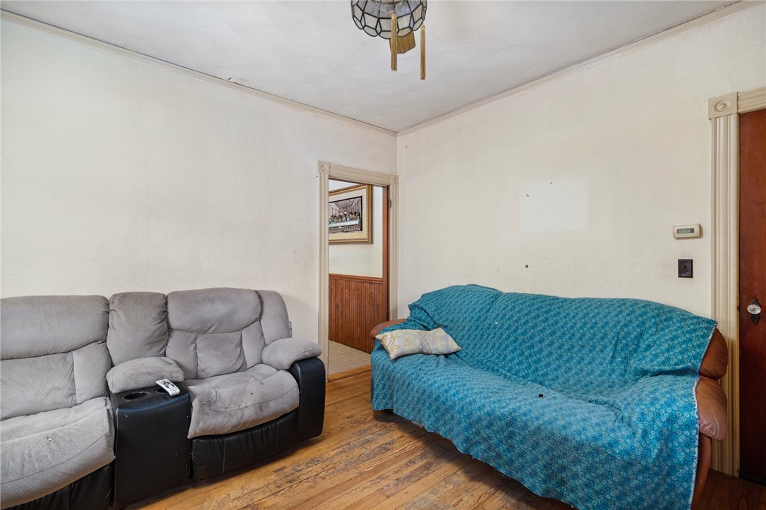Living room with gray reclining sofa, blue-covered sofa, and worn hardwood floors.