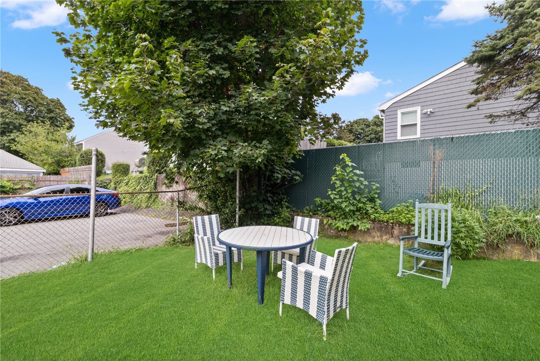 Fenced backyard with lawn seating beneath a large shade tree.