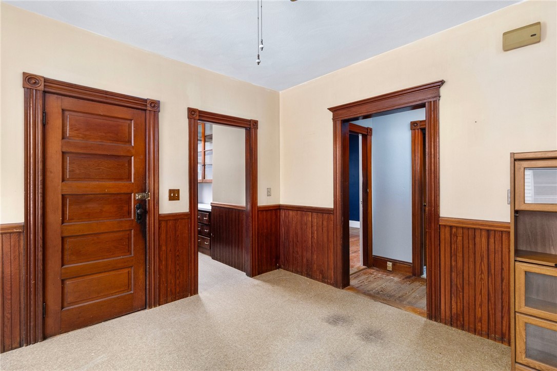 Hallway with dark wood wainscoting, ornate doorways, and light carpeting.