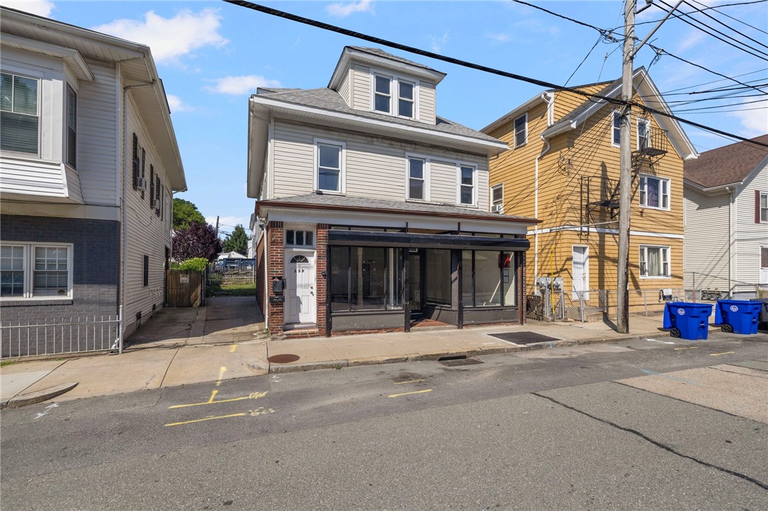 Two-story building with a wide glass storefront and gray-sided upper floors.