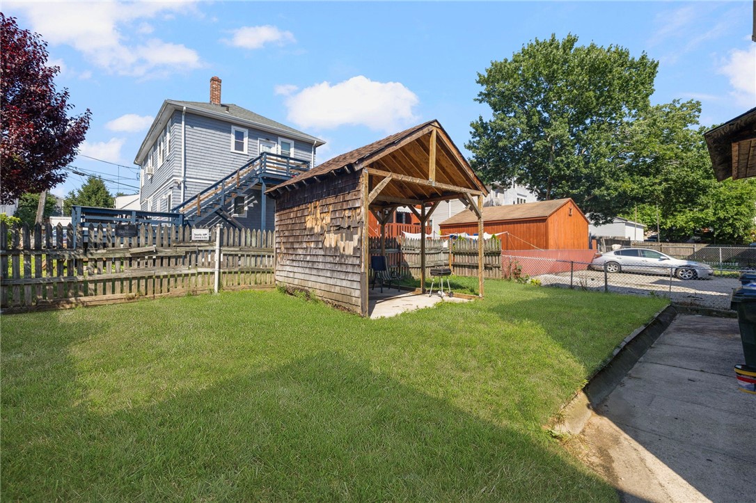 Backyard lawn with a wooden gazebo and fenced boundaries.