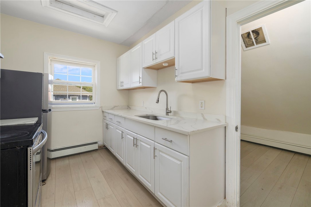Kitchen with white cabinets, marble-look counters, a stainless sink, and black appliances.