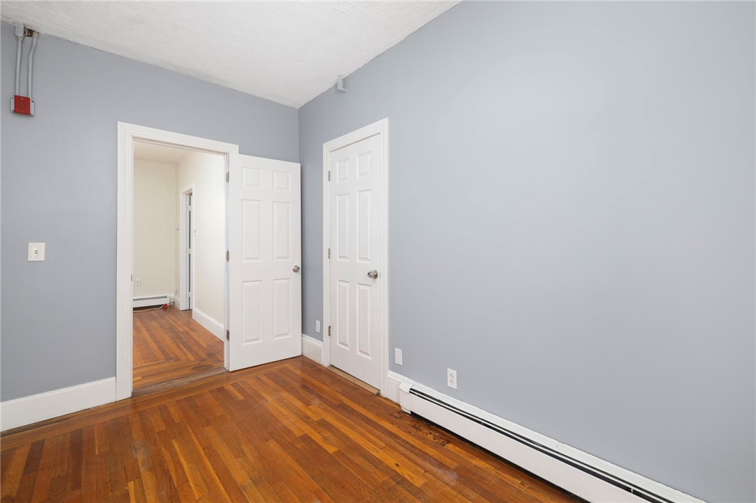 Empty room with polished hardwood floors, gray walls, and two white doors.